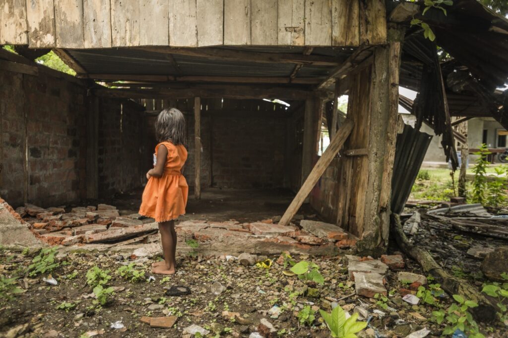 A child stands outside a post-disaster home in Latin America © Miyamoto International