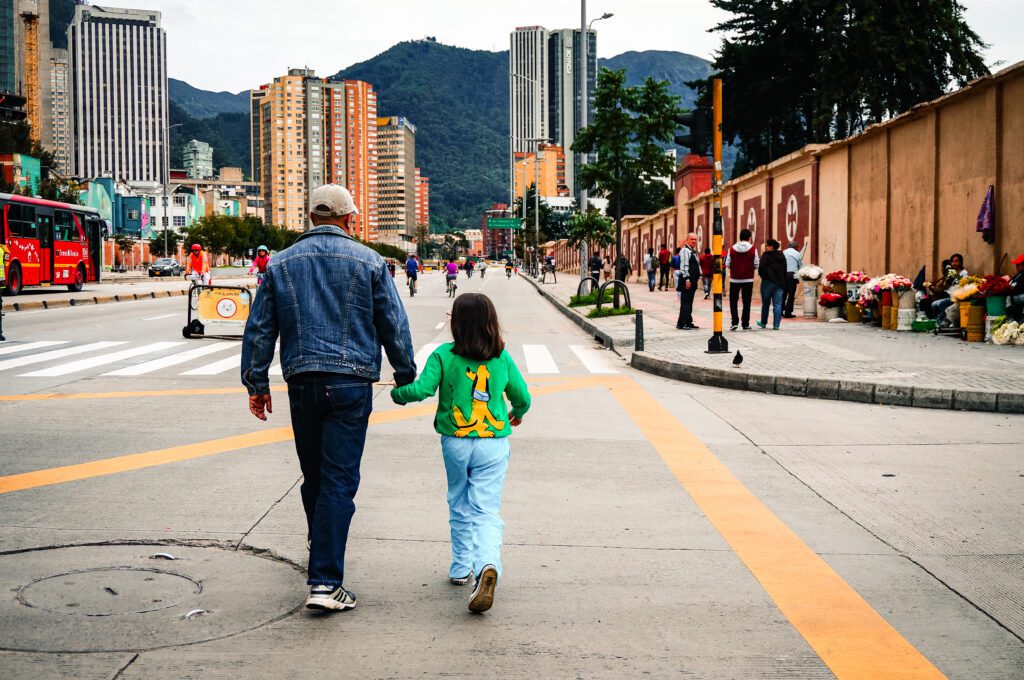 Bogota, Colombia - November 05, 2017: Father and daughter walking across El Dorado Avenue on a Sunday morning during the cultural, sporting event Ciclovia; people go out to work out, specially biking.